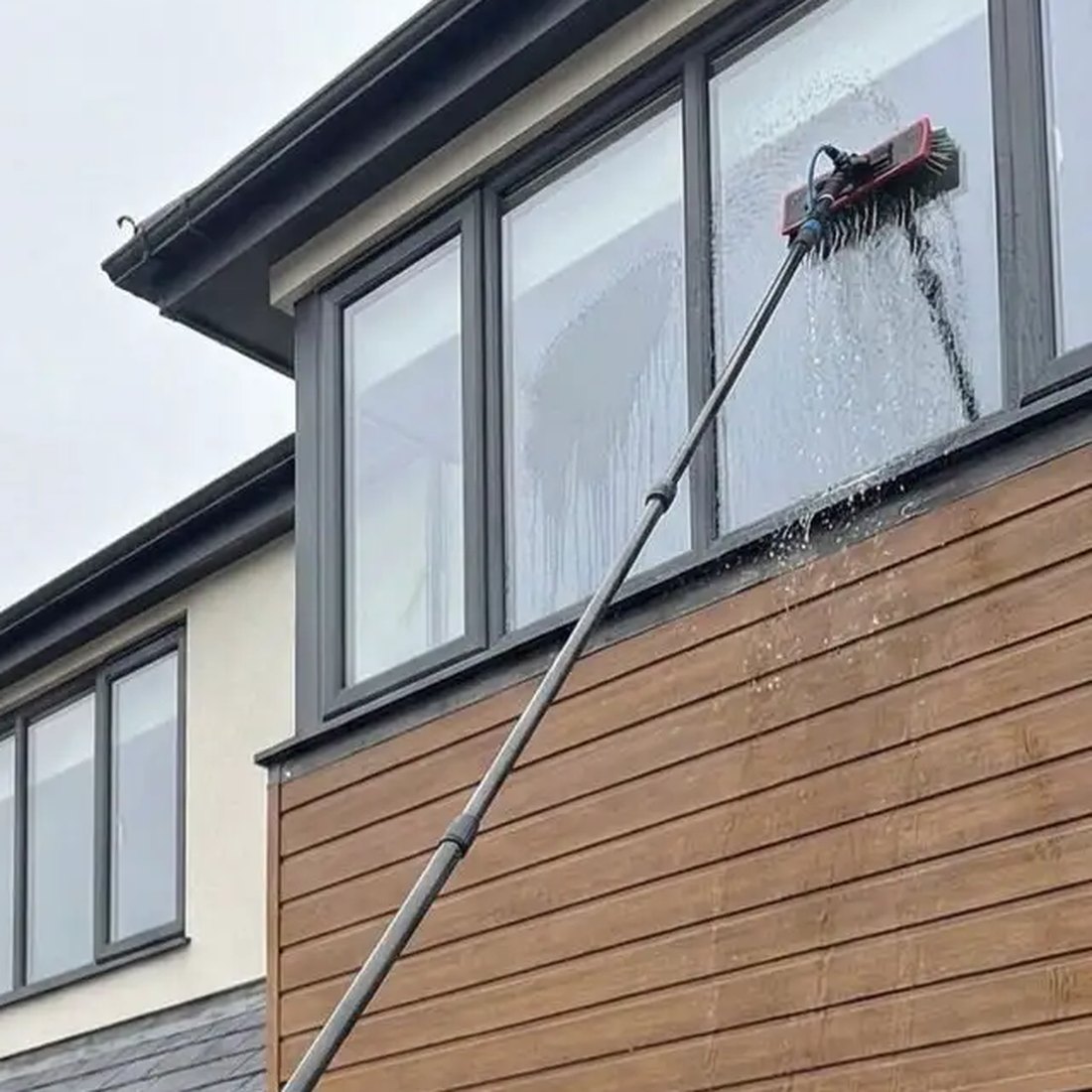 Pure water brush cleaning an upstairs window on a house in Wickford